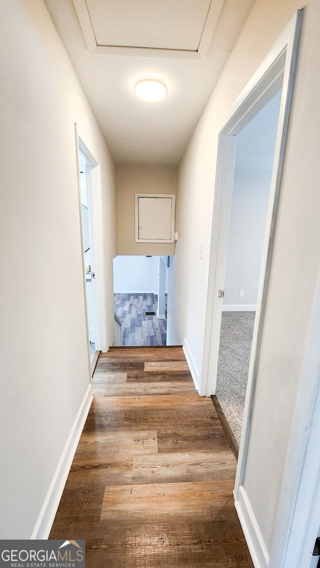 corridor featuring attic access, baseboards, and wood finished floors