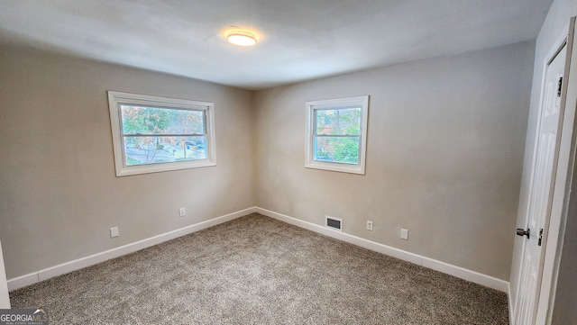 unfurnished room with carpet, visible vents, and baseboards