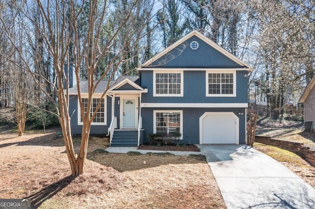 split level home featuring a garage, concrete driveway, and stucco siding