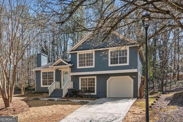 tri-level home featuring a garage, driveway, a chimney, and stucco siding