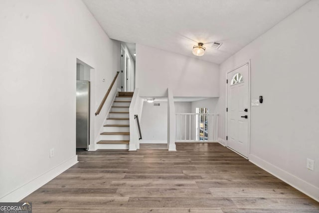 entryway featuring visible vents, stairway, baseboards, and wood finished floors