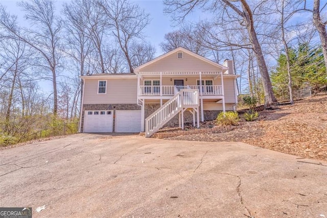 view of front of house featuring concrete driveway, stone siding, a chimney, stairs, and a porch