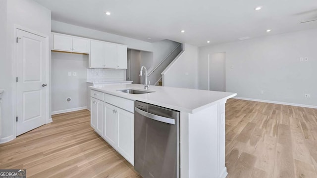 kitchen featuring a center island with sink, stainless steel dishwasher, light wood-style floors, white cabinetry, and a sink