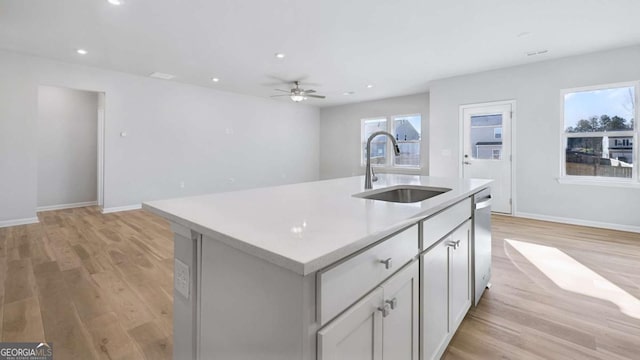 kitchen featuring recessed lighting, light countertops, light wood-style flooring, stainless steel dishwasher, and a sink