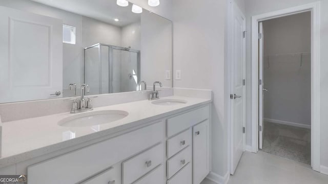 full bath with a walk in closet, a sink, a shower stall, and double vanity