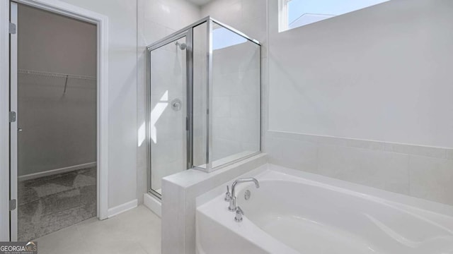 bathroom featuring a stall shower, tile patterned flooring, a garden tub, and a walk in closet