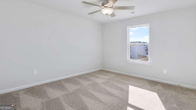 carpeted spare room featuring baseboards, visible vents, and a ceiling fan