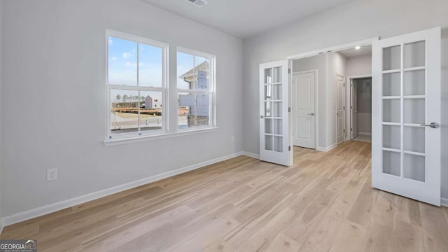 spare room with baseboards, french doors, visible vents, and light wood-style floors