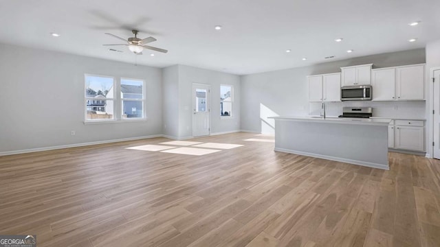 kitchen with stainless steel appliances, open floor plan, and light wood finished floors