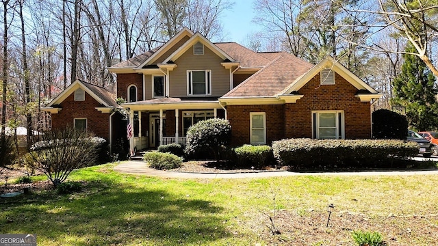 craftsman-style house featuring brick siding, covered porch, and a front lawn