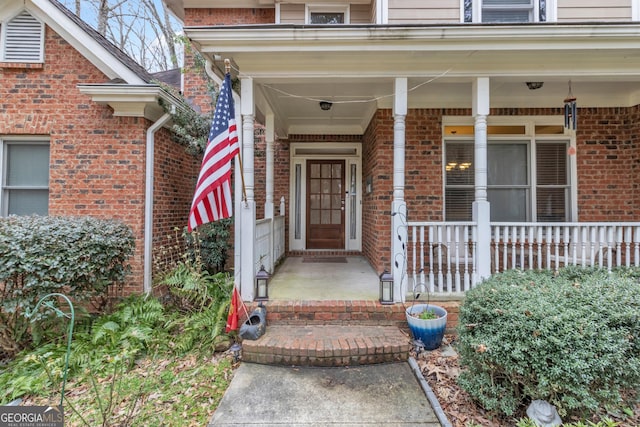 doorway to property with brick siding and a porch