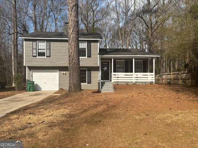 split level home with driveway, covered porch, an attached garage, and fence