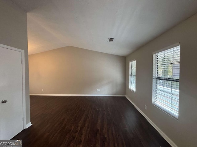 spare room with lofted ceiling, dark wood-type flooring, visible vents, and baseboards