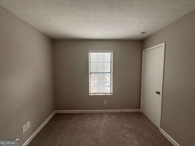 empty room with carpet, a textured ceiling, and baseboards