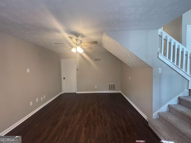 bonus room featuring stairs, a textured ceiling, wood finished floors, and visible vents