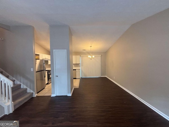 interior space with a notable chandelier, lofted ceiling, stairway, light wood-type flooring, and baseboards