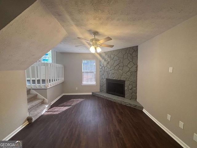 unfurnished living room with a fireplace, a ceiling fan, a textured ceiling, wood finished floors, and baseboards