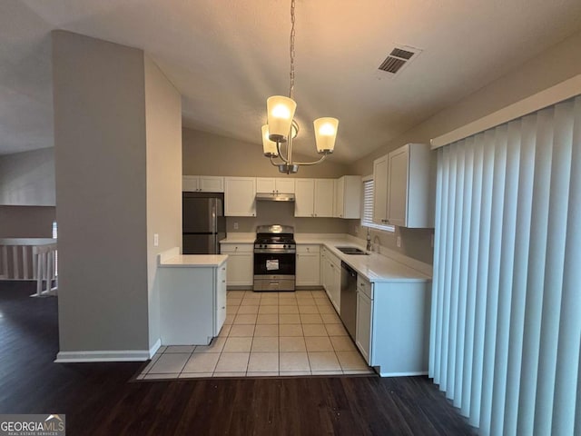 kitchen with light wood finished floors, stainless steel appliances, light countertops, white cabinets, and a sink