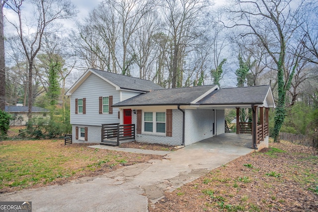 split level home with an attached carport, brick siding, concrete driveway, and a shingled roof