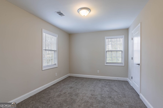 spare room with carpet, baseboards, and visible vents