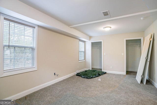 unfurnished bedroom featuring visible vents, multiple closets, carpet floors, and baseboards