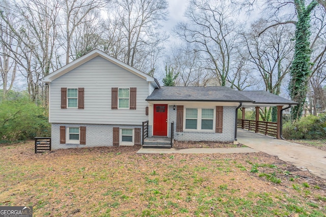 tri-level home featuring a carport, brick siding, and driveway