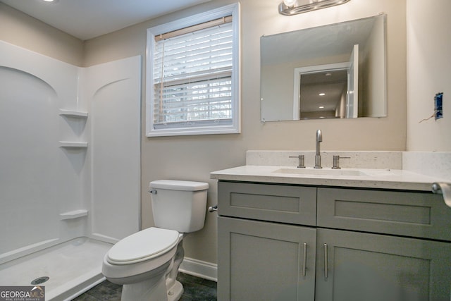 full bath featuring vanity, a shower stall, toilet, and baseboards