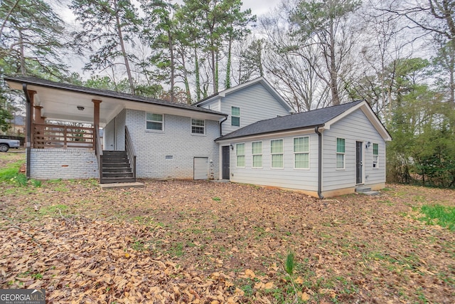 rear view of house featuring brick siding and a porch