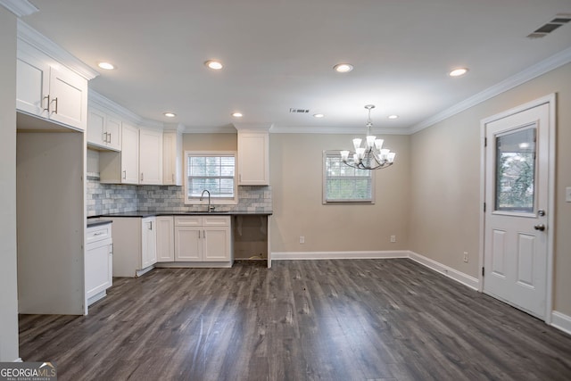 kitchen featuring tasteful backsplash, visible vents, crown molding, dark wood-style flooring, and a sink