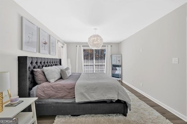 bedroom featuring dark wood finished floors, baseboards, and an inviting chandelier