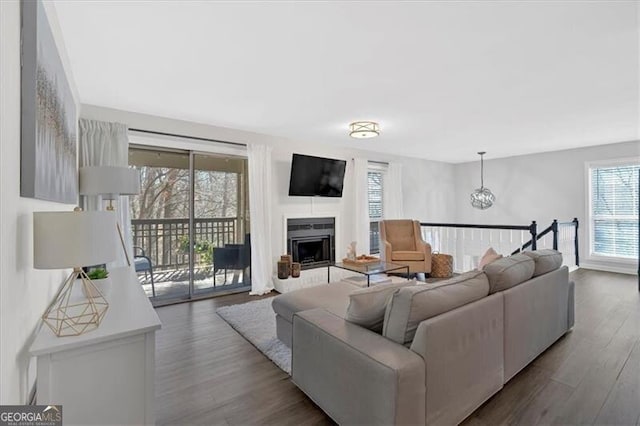 living area featuring a notable chandelier, a fireplace, and dark wood-type flooring