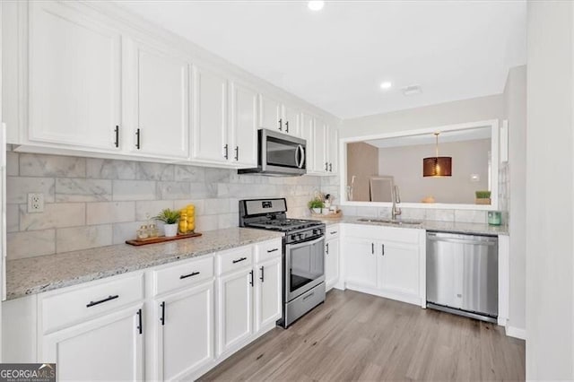 kitchen with stainless steel appliances, backsplash, a sink, and white cabinetry