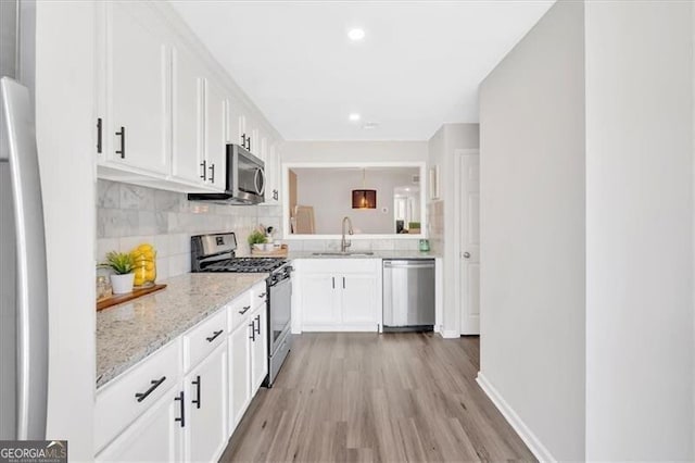 kitchen with stainless steel appliances, a sink, white cabinetry, and decorative backsplash