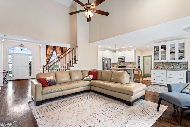 living room featuring decorative columns, recessed lighting, stairway, a high ceiling, and wood finished floors