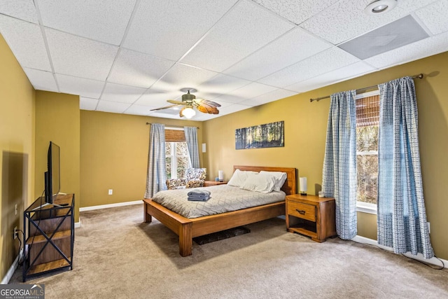 carpeted bedroom featuring ceiling fan, a drop ceiling, and baseboards