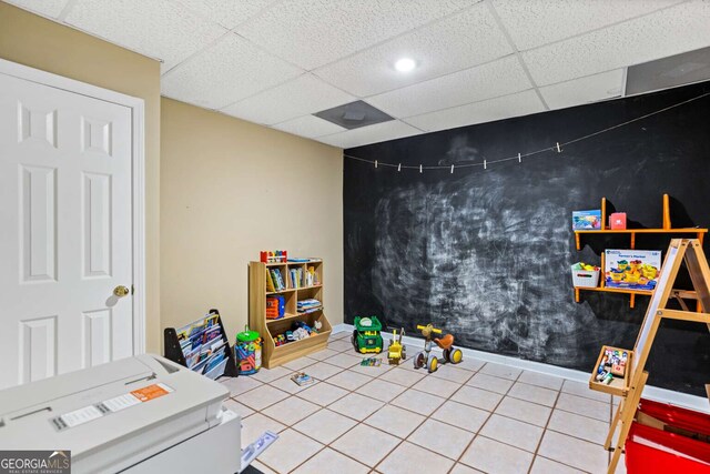 game room featuring an accent wall, tile patterned flooring, and a drop ceiling