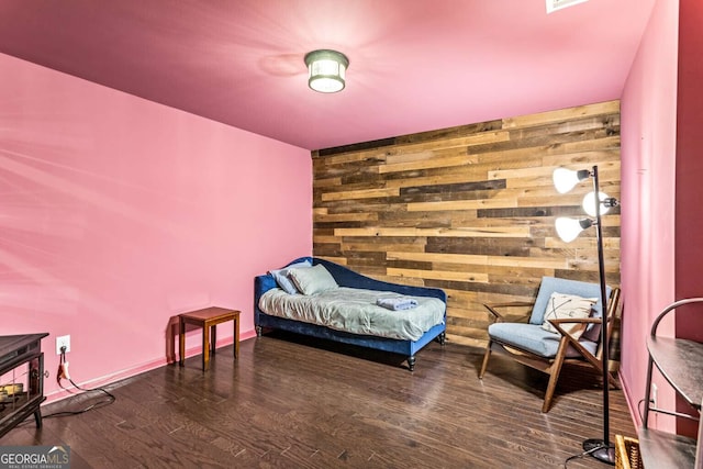 bedroom with an accent wall, wooden walls, baseboards, and wood finished floors