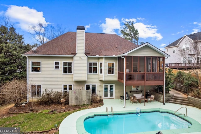 rear view of house with fence, a sunroom, french doors, a chimney, and a patio area