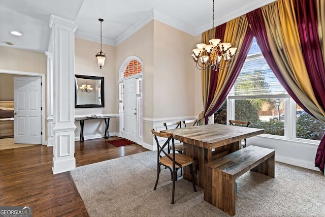 dining space with decorative columns, a chandelier, wood finished floors, and ornamental molding