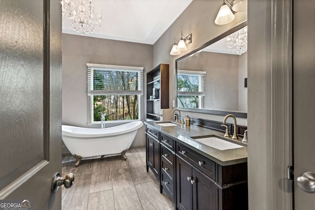 full bath with a freestanding tub, a notable chandelier, a sink, and double vanity