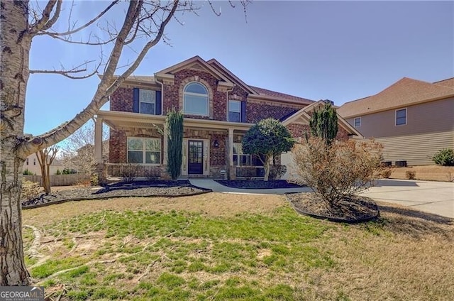 view of front of house with brick siding, driveway, and a front lawn