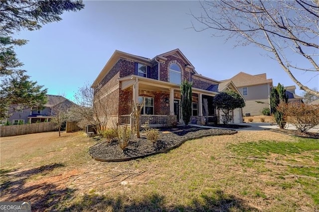 traditional-style home with covered porch, driveway, brick siding, and a front lawn