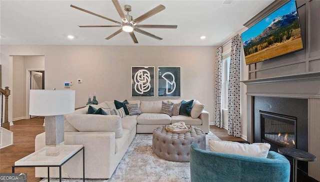 living area featuring recessed lighting, ceiling fan, wood finished floors, and a glass covered fireplace