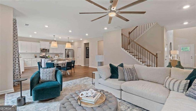 living area with recessed lighting, visible vents, baseboards, stairway, and light wood-type flooring