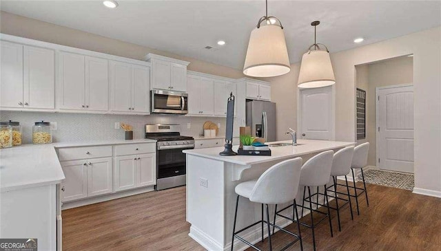 kitchen featuring an island with sink, dark wood-style floors, appliances with stainless steel finishes, white cabinetry, and a sink