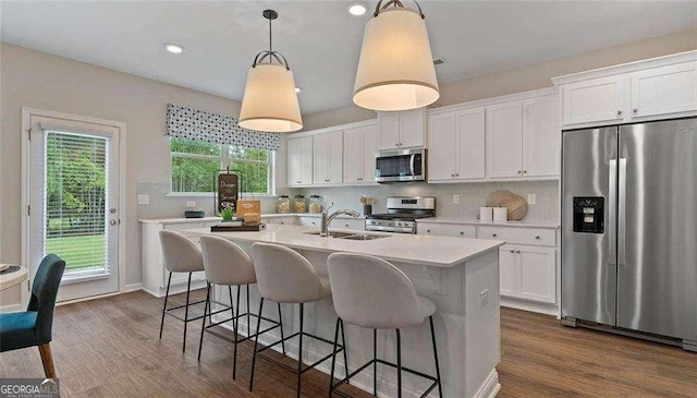 kitchen with light countertops, backsplash, appliances with stainless steel finishes, white cabinetry, and a sink