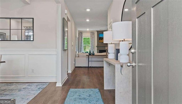 hall with a decorative wall, wood finished floors, and wainscoting