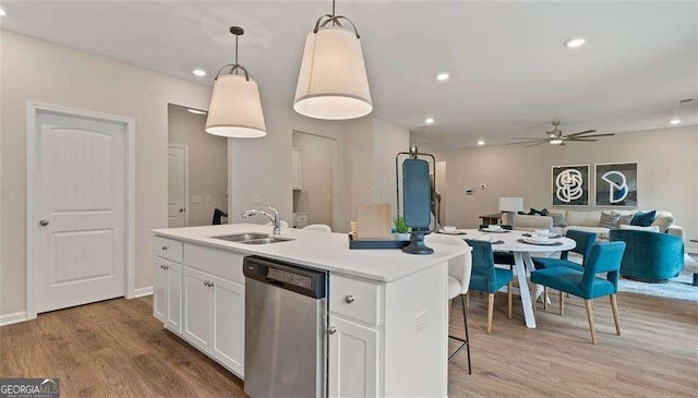 kitchen with a kitchen island with sink, white cabinetry, a sink, wood finished floors, and dishwasher