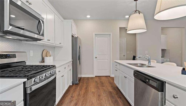 kitchen with dark wood finished floors, appliances with stainless steel finishes, light countertops, white cabinetry, and a sink