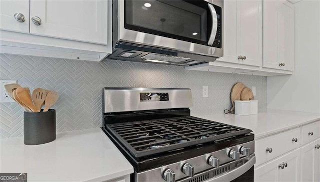 kitchen with stainless steel appliances, light countertops, and white cabinetry